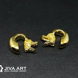 May include: Two gold-coloured ear gauges featuring a dragon design. The gauges are made of metal and have a smooth finish.