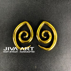 May include: A pair of gold-colored spiral ear gauges. The gauges are made of metal and have a swirl design. The gauges are handcrafted and are a popular choice for body jewelry.