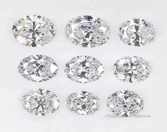 May include: Nine oval-shaped, clear, faceted gemstones arranged in three rows on a white background.  The gemstones are different sizes, with the largest in the top row.