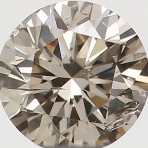 Puede incluir: Un diamante de talla redonda con un tono marrón claro. La gema tiene numerosas facetas que reflejan la luz, creando un efecto brillante. El diamante se encuentra sobre un fondo blanco liso, resaltando su brillo.