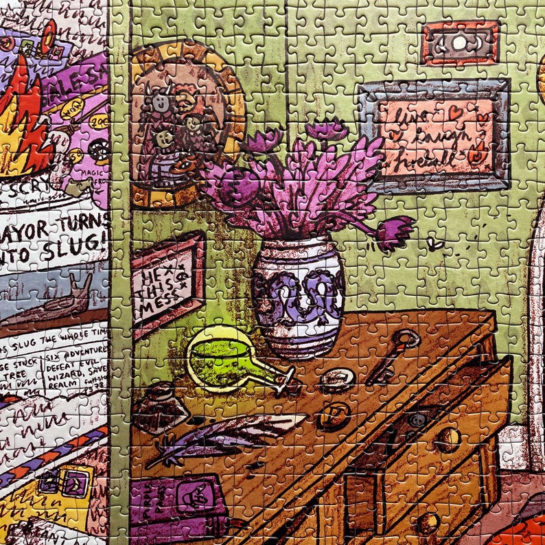 May include: A colorful jigsaw puzzle featuring a whimsical illustration. The puzzle depicts a wooden desk with a vase of purple flowers, a green potion bottle, and framed artwork. Text includes "Mayor Turns Into Slug!" and "Live, Laugh, Fireball!"