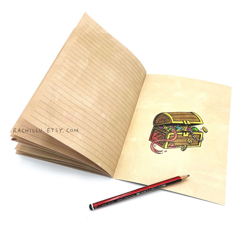 May include: An open lined journal with a brown cover. The right page has a hand-drawn illustration of a treasure chest overflowing with jewels and coins. The text "rachillu.etsy.com" is printed on the left page. A red pencil is lying on the open journal.
