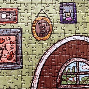 May include: A completed jigsaw puzzle featuring a cartoon illustration of a room interior. The puzzle pieces are primarily green, with brown and orange accents. The image includes framed pictures and a window with a view of trees.