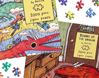 May include: Two 1000 piece jigsaw puzzles by Rachillu titled Rainbow Dragon and Beware of the Dragon. The boxes feature colorful illustrations of red dragons and blue birds, with scattered puzzle pieces visible on a white surface.