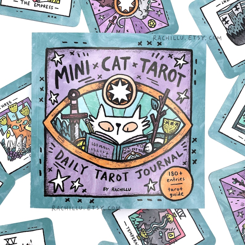 May include: A purple and teal journal cover with a cat illustration and the text "MINI CAT TAROT DAILY TAROT JOURNAL BY RACHILLU 180+ entries tarot guide".