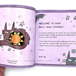 May include: A purple daily tarot journal with a cat and sun illustration on the front cover. The text on the cover reads "Welcome to Your Daily Tarot Journal!" and includes the website "rachillu.etsy.com".