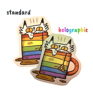 Pu&ograve; includere: Due adesivi raffiguranti un gatto bianco che sbuca da una tazza a righe arcobaleno. Uno &egrave; standard, l'altro olografico. La parola "standard" &egrave; sopra il primo adesivo e "holographic" sopra il secondo.
