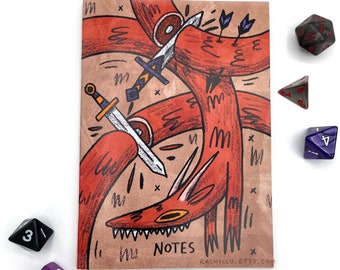 May include: A brown notebook with a red fox illustration on the cover. The fox is surrounded by swords and arrows. The notebook has the word "NOTES" printed on the cover.