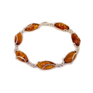 May include: A silver bracelet with six amber oval-shaped stones. The stones are set in a silver wire design.