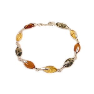 May include: A silver bracelet with amber stones in shades of green, yellow, and brown. The stones are oval shaped and set in a twisted silver design.