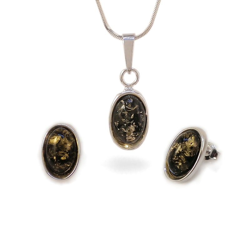 May include: A silver necklace and earrings set with oval-shaped green amber stones.