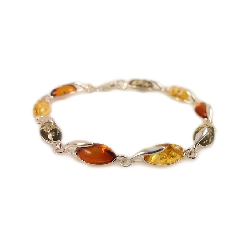 May include: A silver bracelet with oval-shaped amber beads in shades of green, yellow, and brown.