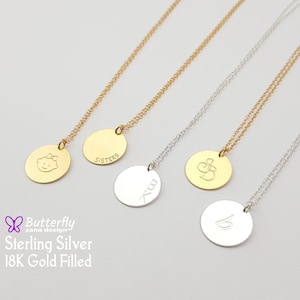 Pode incluir: Quatro colares de prata e ouro com pingentes redondos. Os pingentes são gravados com as palavras "Sisters", "K", "S&D" e "b".