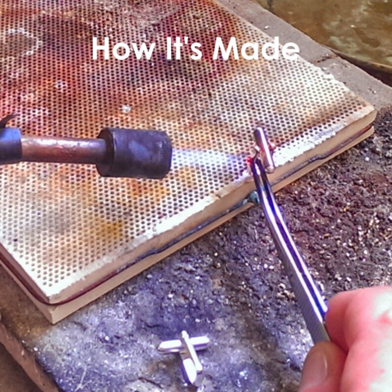 May include: A close-up of a metal piece being heated with a torch. The metal piece is held in place with tweezers on a ceramic tile. The text "How It's Made" is visible at the top of the image.
