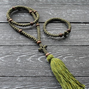 May include: A green prayer rope with wooden beads and a tassel. The rope is knotted and has a cross at the end.