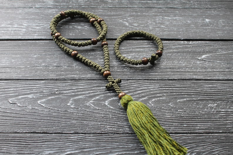 May include: A green prayer rope with wooden beads and a tassel. The rope is knotted and has a cross at the end.