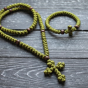K&ouml;nnte beinhalten: Ein gr&uuml;nes, gekn&uuml;pftes Rosenkranzband mit Holzperlen und einem Kreuzanh&auml;nger, sowie ein passendes gr&uuml;nes, gekn&uuml;pftes Armband mit Holzperlen und einem Kreuzanh&auml;nger.