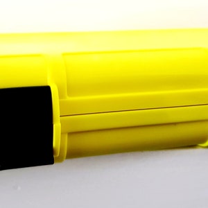 Pode incluir: Uma caixa de plástico rígido amarelo brilhante com travas pretas. A caixa é projetada para proteger e armazenar itens pequenos.