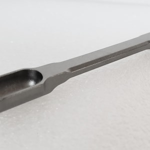 Peut inclure: Un outil en métal argenté avec une cuillère arrondie à une extrémité et un manche plat à l'autre.