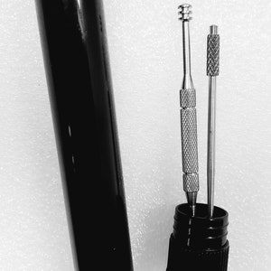 May include: Two silver tools with black handles in a black tube. The tools are used for cleaning pipes.