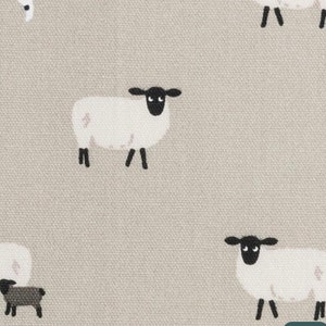 A beige fabric with a repeating pattern of black and white sheep. The sheep are simple illustrations with black eyes and legs.
