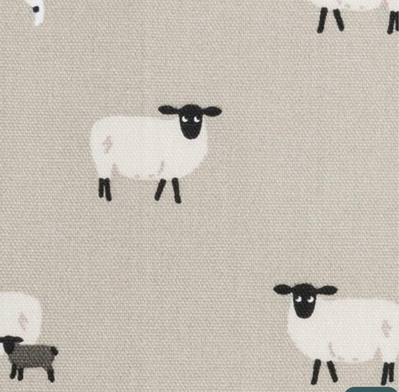 A beige fabric with a repeating pattern of black and white sheep. The sheep are simple illustrations with black eyes and legs.