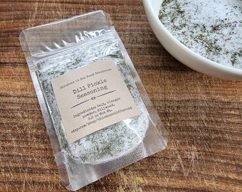 May include: A clear plastic pouch containing a 2.5 ounce package of dill pickle seasoning. The label reads "Chicken in the Road Bakehouse Dill Pickle Seasoning" and lists the ingredients as "Salt, vinegar powder, dillweed".