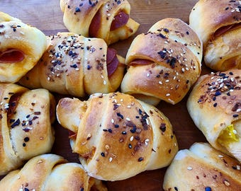 May include: Close-up of a group of crescent rolls filled with pepperoni and cheese, topped with sesame seeds and black and white poppy seeds.