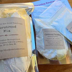 May include: Three clear plastic bags containing dry mixes for cornbread, cornbread dressing, and poultry gravy. The bags are labeled with the name "Chickens in the Road Bakehouse" and list the ingredients for each mix. The cornbread mix is 16 ounces.
