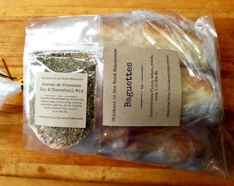May include: Two clear plastic bags containing a small bag of dried herbs labelled "Herbes de Provence Dip & Cheeseball Mix" and two frozen baguettes labelled "Baguettes". The ingredients for the baguettes are listed as "Flour, water, yeast, salt. 1 lb Net Wt."