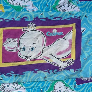 Op de afbeelding: Een Casper de Vriendelijke Geest kussensloop. De kussensloop heeft een grote afbeelding van Casper met het woord "Casper" erboven. De achtergrond is lichtblauw met Casper-geestfiguren en golfpatronen.