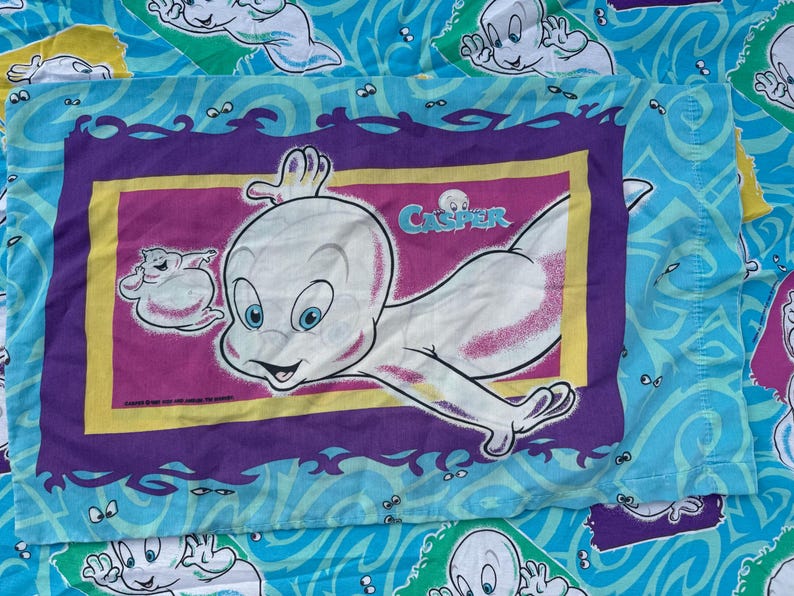 Op de afbeelding: Een Casper de Vriendelijke Geest kussensloop. De kussensloop heeft een grote afbeelding van Casper met het woord "Casper" erboven. De achtergrond is lichtblauw met Casper-geestfiguren en golfpatronen.