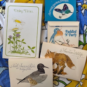 May include: A collection of vintage nature-themed cards and stationery. The items include a box labeled "current garden friends" with a butterfly illustration, and cards featuring birds, foxes, and daisies. The text "Daisy Time" is visible on one card.