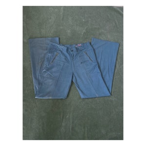 May include: A pair of blue denim pants with zippered pockets and a wide leg style.