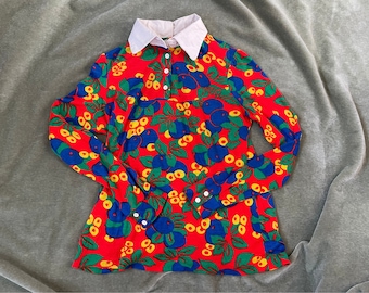 May include: A red long-sleeved shirt with a white collar and a colorful floral pattern featuring blue, green, and yellow flowers.