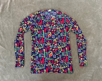 May include: A long-sleeved shirt with a blue background and a colorful abstract pattern. The pattern features geometric shapes in red, yellow, green, and blue.