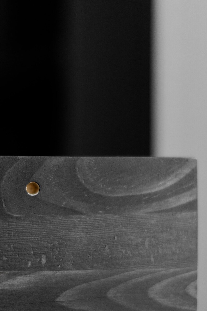 Puede incluir: Primer plano de una superficie de madera oscura con un peque&ntilde;o tornillo redondo dorado en el centro.