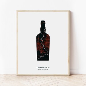 Puede incluir: Una ilustración en blanco y negro de una botella de vino con la ciudad de Lethbridge, Alberta, Canadá, delineada en rojo. El texto "Lethbridge 49.6895° N, 112.8418° W" está debajo de la botella.