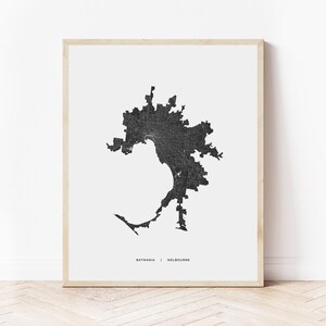 May include: Black and white print of a map of Melbourne, Australia. The map shows the city's streets and neighborhoods. The print is framed in a simple wooden frame and is ready to hang on a wall.