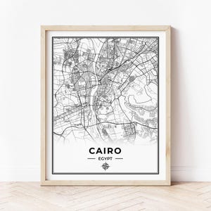 May include: Black and white map print of Cairo, Egypt with the city name and country name in a simple font. A compass symbol is below the text.