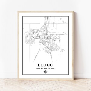 May include: A black and white map of Leduc, Alberta, with a compass rose in the bottom center. The city name and province are printed below the map.