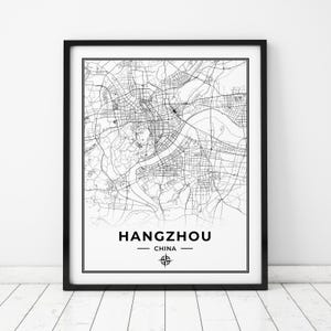 Op de afbeelding: Zwart-witte kaartprint van Hangzhou, China, met de naam van de stad en de naam van het land onder de kaart. Onder de naam van het land is een kompas symbool gedrukt.