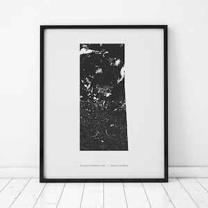 May include: Black and white map print of Saskatchewan, Canada, with the text "KISISKACHEWANI SIPI | SASKATCHEWAN" at the bottom.