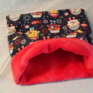 May include: A red and blue fabric pet bed with a robot pattern. The bed is made of soft, plush fabric and has a cozy, cave-like design.