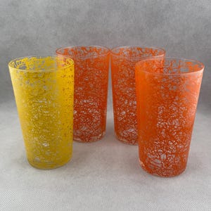 May include: Set of four vintage drinking glasses with a unique design. Two glasses are orange with a yellow criss-cross pattern, and two glasses are yellow with an orange criss-cross pattern.