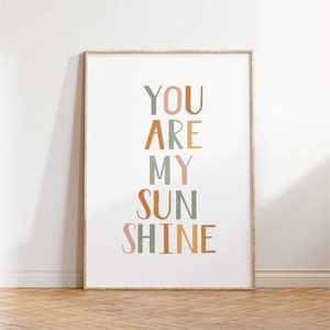 May include: A framed print with the text "YOU ARE MY SUNSHINE" in a vertical arrangement. The letters are in different colors, including green, orange, and pink.
