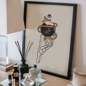 May include: Black and white illustration of a skeletal hand holding a bottle with a ribbon that says "Plant Potion". The illustration is on a beige background and framed in black.