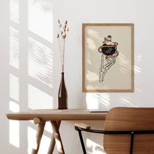 May include: A black and white illustration of a skeletal hand holding a round glass bottle with a cork stopper. The bottle is tied with a bright orange ribbon. The background is a light beige.