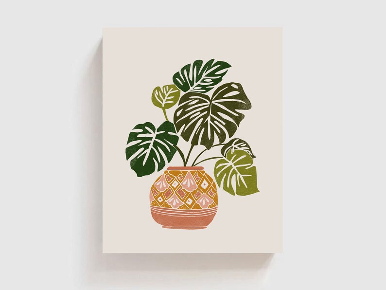 May include: A green leafy plant with large leaves in a terracotta pot with a geometric pattern. The pot is a warm orange color with pink and white accents.