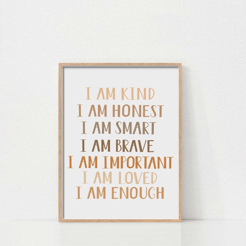 May include: A framed print with the words "I AM KIND, I AM HONEST, I AM SMART, I AM BRAVE, I AM IMPORTANT, I AM LOVED, I AM ENOUGH" in various shades of brown. The print is in a light brown wooden frame.